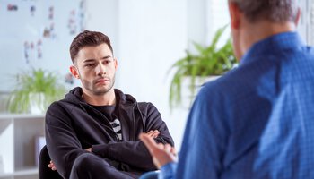 Junger Mann im Gespräch mit seinem Therapeuten | © Iza Habur - izusek - Getty Images